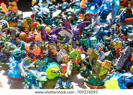 group of dragons, knights, monsters and other small plastic figurines sold at charity, flea market or thrift store for symbol of over-consumption and waste, outdoors