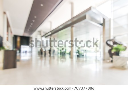 Hotel or office building lobby blur background interior view toward reception hall, modern luxury white room space with blurry corridor and building glass wall window Royalty-Free Stock Photo #709377886