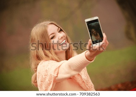 Nature outdoor internet technology concept. Cheerful blonde girl taking selfie. Young gorgeous lady takes picture of herself in autumnal forest.
