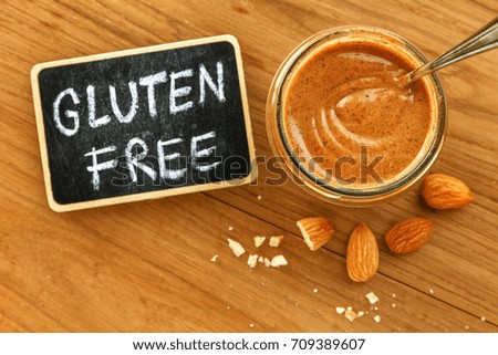 Almond butter in jar with gluten free sign on wooden table top view