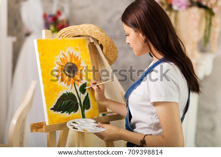 Getting creative. Woman artist painting a sunflower at home studio