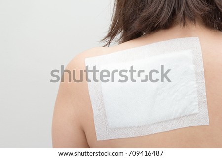 medicated pain relief patch in back of female Royalty-Free Stock Photo #709416487