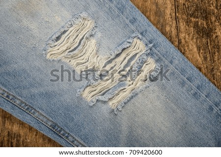 Blue leg torn jeans on old wooden texture .background