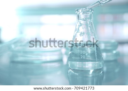pipette drop water in flask with blur petri dish in medical science laboratory background  Royalty-Free Stock Photo #709421773