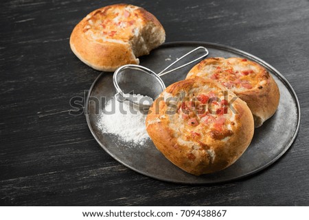 Homemade pies of puff pastry with tomato, ham and cheese cooking on wooden black table background. Mini pizza.