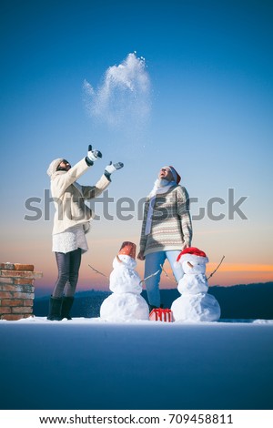 Family snowman. Couple in love. Christmas happy day. Love story. Outdoor happy couple in love posing in cold winter weather. Young boy and girl having fun outdoor. Fashion image. Happy family. Snow