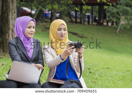 Two beautiful muslim women are discussing and taking picture at public park