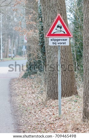 Road sign warning against slippery road due to snow ice (dutch)