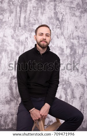  young man in a simple dark clothes posing in Studio on a background of a fragment of the old grey walls. short hair and clean skin. Wallpapers for your desktop. business portrait