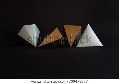Gold silver minimalistic design geometric solid figures on black. Elegant prism pyramid triangle shape solid objects, paper background. 