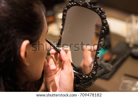 Close Up Asian woman concentrate to applying make up (paint her eyelashes) with the mirror for working time. Skin care Cosmetics concept.
