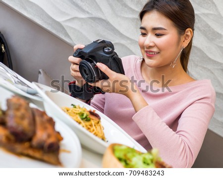 Women hold a camera in a hand and taking a picture for review in her blog.