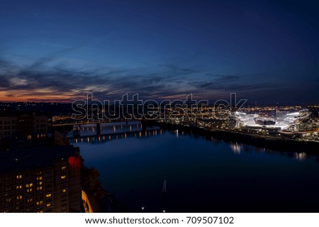 A sunset view of the Ohio River and a lit football stadium in Cincinnati, Ohio.
