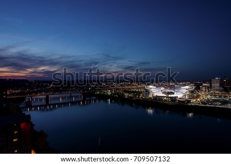 A sunset view of the Ohio River and a lit football stadium in Cincinnati, Ohio.