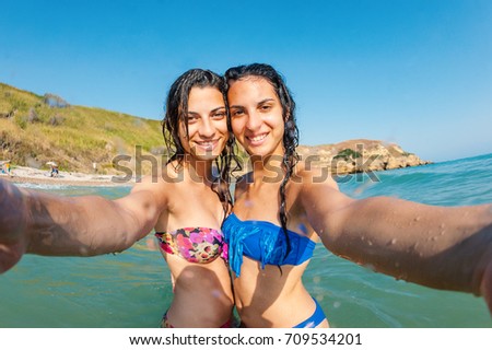 Young sisters portrait having fun together taking a picture at the sea. Lifestyle concept.