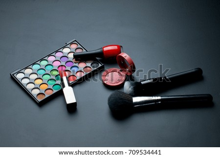Set of cosmetics and makeup brushes on a black background.