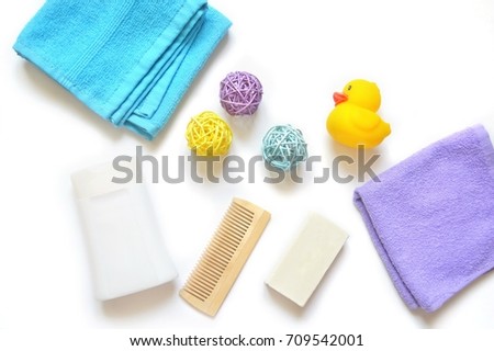 Blue and purple towels, white shampoo bottle, wooden comb, baby soap, yellow rubber toy. Flat lay bath products, natural cosmetics, shower items. Beauty background for site, stock photo 