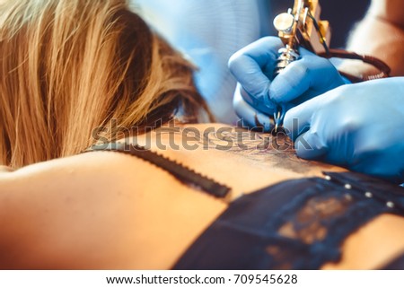 tattooer showing process of making a tattoo, hands holding a tatoo machine