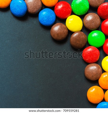 Multicolored sweets in the form of a dragee on a dark background