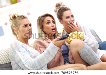 Three beautiful young women watching tv at home
