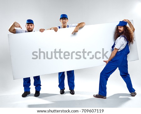 Conceptual picture of three crafstmen holding an empty, white board