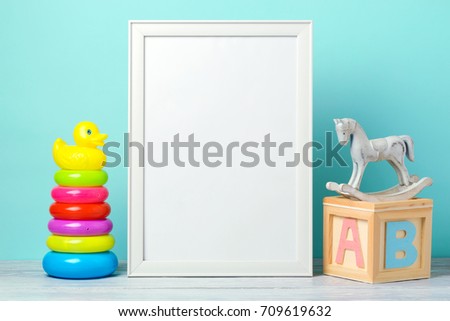 Frame mock up on wooden table with toys. Nursery or kids room interior background