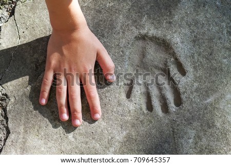 Childs hand and memorable handprint in concrete