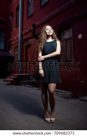 Beautiful brunette young woman wearing dress and walking on the street. Lifestyle in the city. Copy space for design
