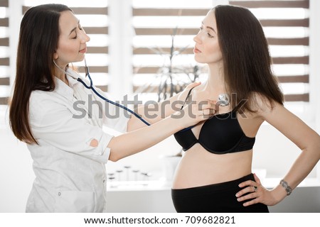 female medicine doctor holding stethoscope to pregnant woman standing for encouragement, empathy, cheering,support, medical examination. New life of abortion concept.