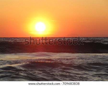 The Mediterranean Sea in the rays of the setting sun. Foam Waves and Sea Sand