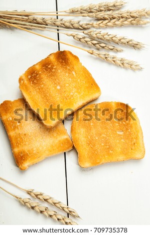 Toasts and wheat on a white wooden background