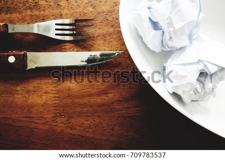 No work No money and No food. The picture of failed work condition consist of disastrously paper on white dish, pencil, fork, spoon, hand and knife above wooden table. selective focus. soft tone style