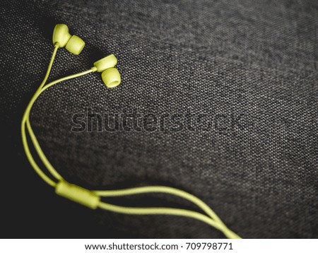 Top view of yellow earbuds on the dark brown sofa background, an accessory of modern technology that popular in this time, this photo with copy space on the right side.