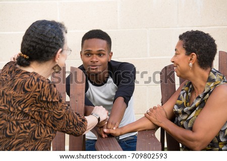 Closeup portrait, young handsome man having conversation with family sitting down, isolated outdoors background Royalty-Free Stock Photo #709802593