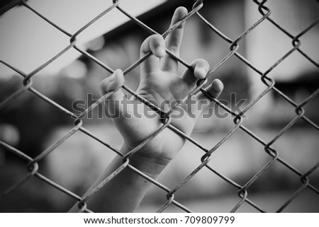 Hand in jail with girl and house of detention concept, vignette effect and selective focus, black and white tone. Royalty-Free Stock Photo #709809799