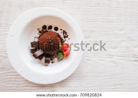Chocolate fondant with decoration from strawberry and mint on wooden table. Delicious dessert serving in restaurant, top view with free space