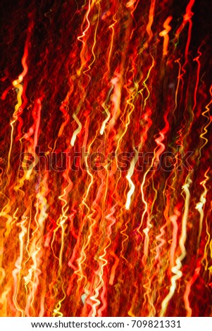 Abstract background of colorful crankles in motion on black. Bokeh of defocused curves, blurred neon yellow and red leds, festive backdrop of fireworks, holidays and celebrations