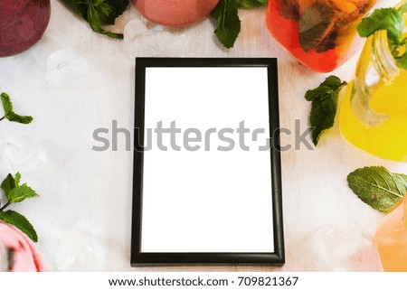 Picture frame laying on table with partially seen fruit drinks around. Food blogs, menu and recipes for web sites of cafe and restaurant, close up picture with copy space