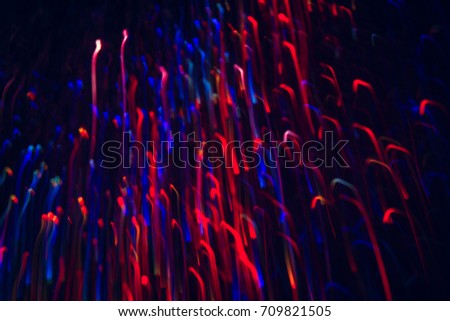 Abstract picture of colorful lines in motion on black background. Bokeh of defocused curves, blurred neon blue and red leds of serpentine, festive backdrop of fireworks, holidays and celebrations