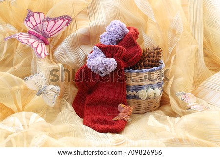 Still life with needlework: a handmade basket with roses and socks with pompoms