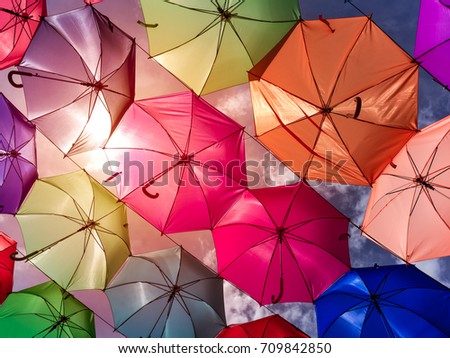 Colorful and beautiful umbrellas above footpath on the street with sunset and blue sky background, summer breeze vacation theme