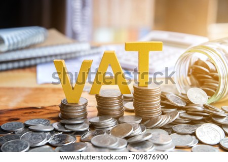 Vat Concept.Word vat with stacked coins there is a notebook calculator on the desk.VAT Royalty-Free Stock Photo #709876900