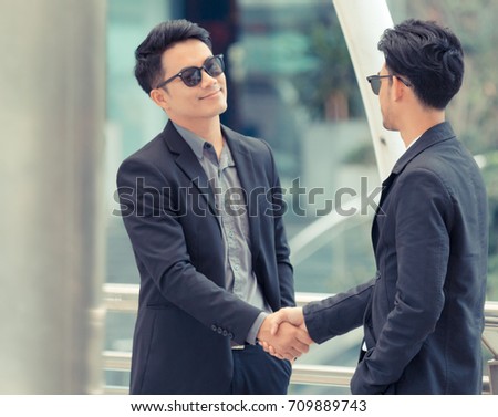 Two smart businessmen are shaking hands closing a deal. Business partners who have a good relationship to each other.