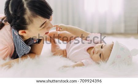 Family portrait of Asian people : 4 months baby feeling happy loving and smiles while playing with her mother.