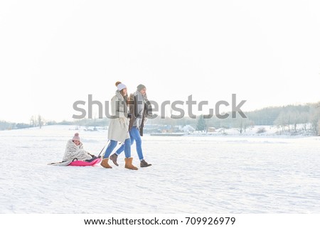 Family playing toboggan on the snow in winter 