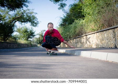 stylish skater in red shirt and blue jeans ride downhill on longboard, summer active picture 