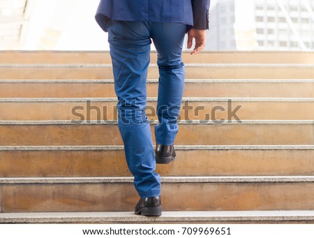 Confident businessman stepping up stair. Royalty-Free Stock Photo #709969651