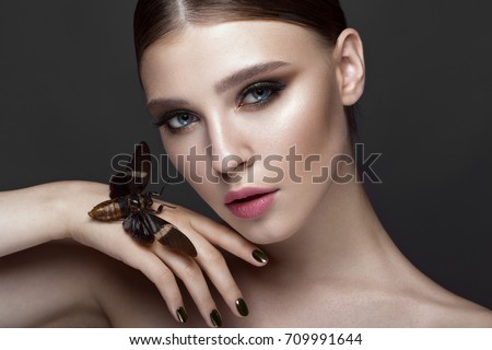 Portrait of beautiful girl with colorful make-up and cicada. Beauty face. Photo taken in the studio.