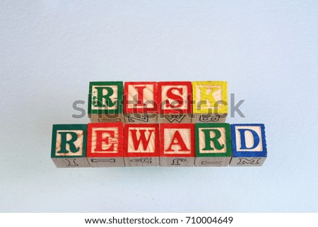The term risk reward visually displayed on a white background using colorful wooden toy blocks in landscape format with copy space