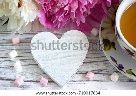 Peonies flowers pink cup of tea rattan hearts marshmallow on a white wooden background - stock image